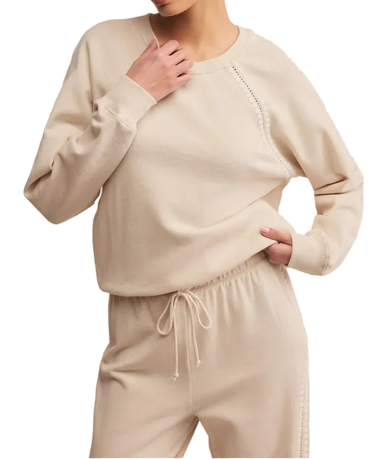 Woman wearing a beige sweater and pants set on a plain background
